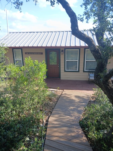 Front of Twenty Mile View Cottage nestled among the oak trees in rural Kerr County, Texas